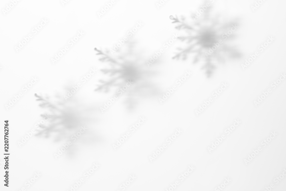Obraz premium Soft snowflake shadows through matte glass on white winter background with copy space for Christmas greeting card, banner or seasonal design