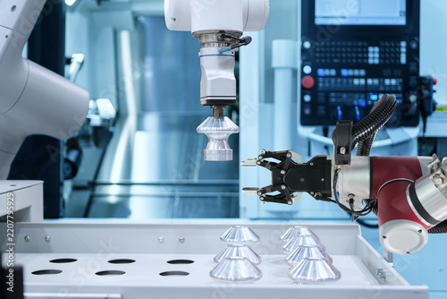 Modern technology with industrial automation gripping robot working with metalwork on CNC machine on smart manufacturing and right copy space, industry 4.0