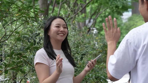 Japanese man and woman meeting on a street corner and chatting with smiles on a date