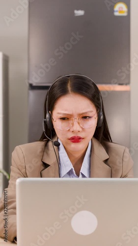 Frustrated Asian Businesswoman Wearing Headset Working on Laptop Remotely