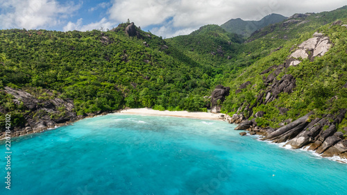 Tropical beach with vibrant green hills and azure ocean. Seychelles. Anse Du Riz beach. Baie Ternay Marine National Park.