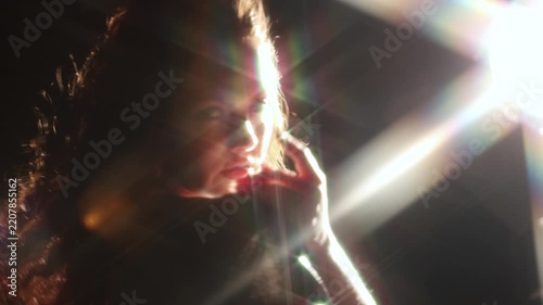Bright light beam covering the face of a woman in a shiny dress. Anonymous figure, star flare and dark space for themes of energy, insight and change.