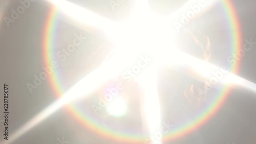 Giant lens flare star with rainbow halo over a silhouette. Optical rays, spectral rings and deep black space for overlays, covers and backgrounds.