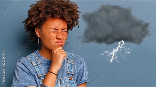 A young woman with curly hair looks thoughtfully at a cloud that darkens and produces lightning, reflecting her changing mood.