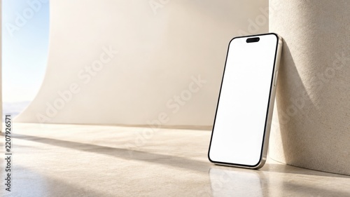 A smartphone with a blank white screen leaning against a curved beige wall in a bright sunny space d