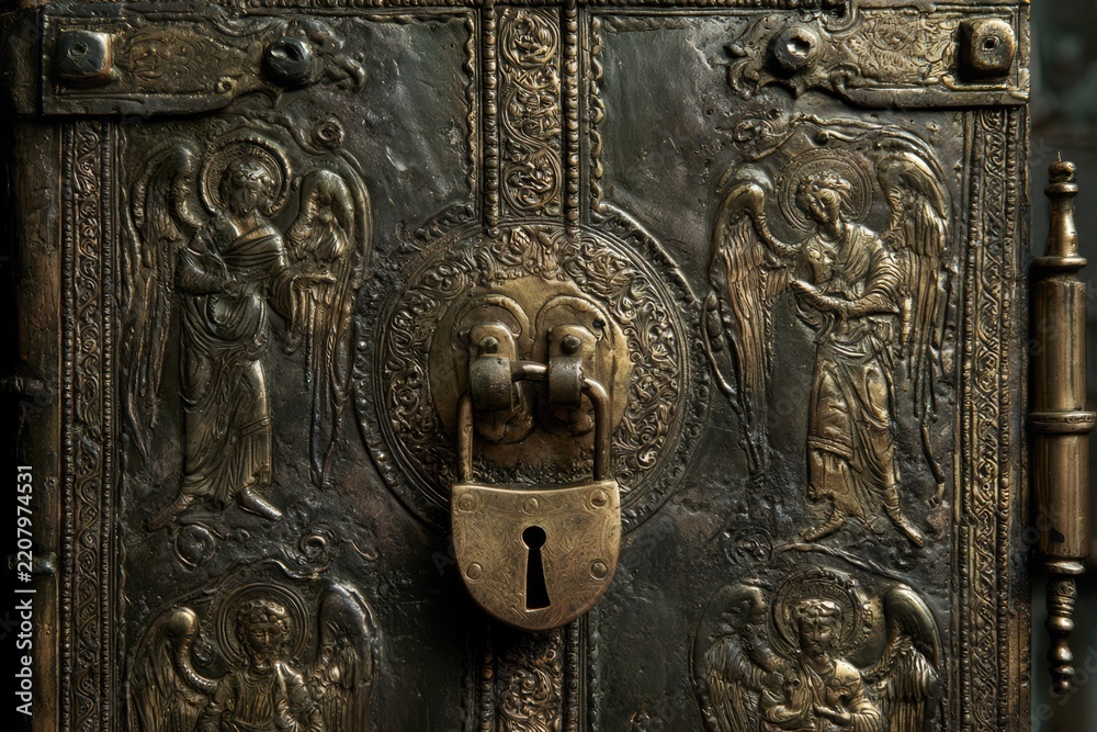 Obraz premium Ornate antique metal book cover featuring angels in relief and a secured padlock