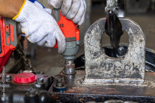 Obraz na plátně A technician operates a power tool to tighten bolts on heavy equipment components