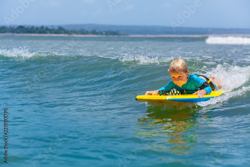 Fotografie Happy young surfer boy with bodyboard have fun on beach, riding on small ocean waves