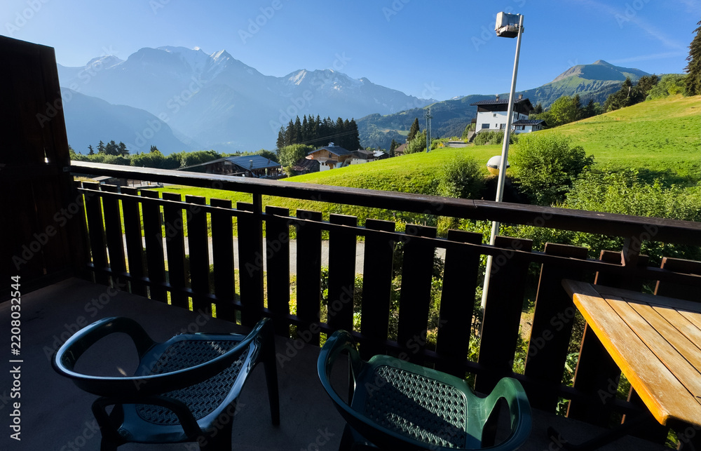 Obraz premium cozy wooden balcony with comfortable lounge chair overlooking scenic green mountains