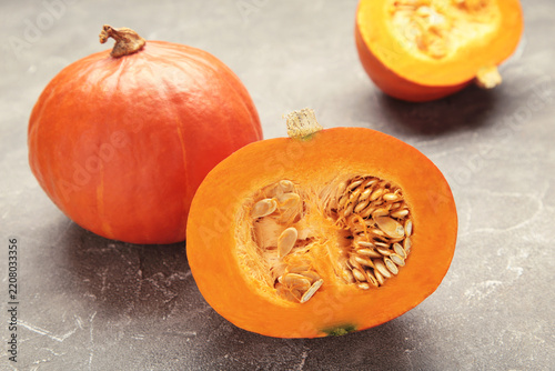 Sliced Hokkaido pumpkin with seeds on grey concrete background.