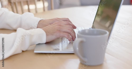 Person's hands are landing on keyboard on wooden table, pressing keys, typing for remote work