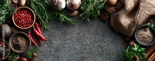 Rustic kitchen Christmas background with spice, herb, garlic, chili, and burlap arrangement on dark stone