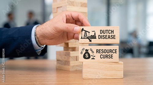 Businessman hand placing wooden block with dutch disease and resource curse text on top of a stack