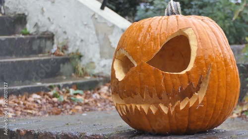 Spooky Halloween Pumpkin Head on Wet Stone Steps Outdoors
