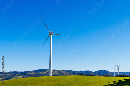 Fotografie Wind turbines generating renewable energy on a green hill near Toora Victoria