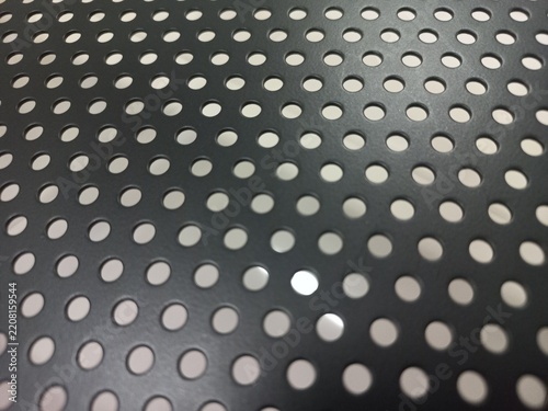 Perforated Black Metal Sheet Texture with Round Holes and White Background.