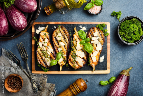 Baked eggplant with cheese and spices on a slate plate. Grilled vegetables. On a gray concrete background.
