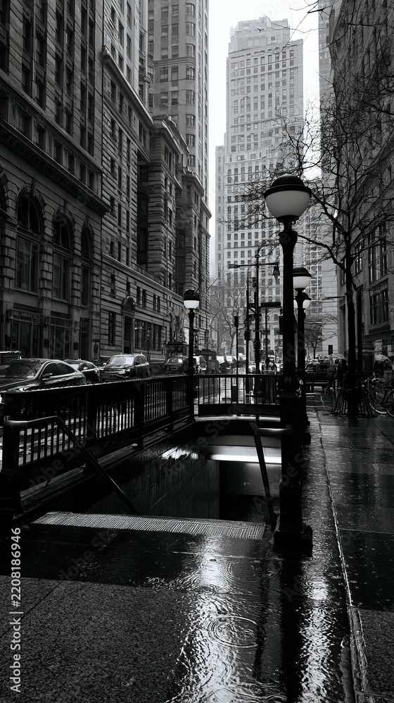 Fototapeta premium Gray Rainy Day at Subway Entrance Surrounded by Tall Buildings and White Skies in Urban City Scene