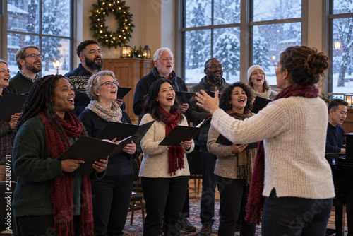 Community choir rehearsing inside a warm civic hall as snow falls