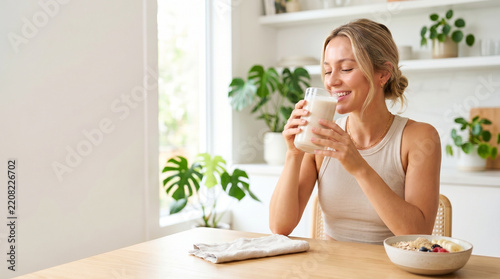 Young woman drinking protein shake slowly in a bright kitchen  