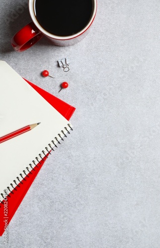 Workplace with notebook, pencil, and red cup of coffee, top vertical view 