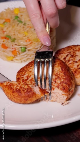Vertical video of hands cutting a fried patty with rice