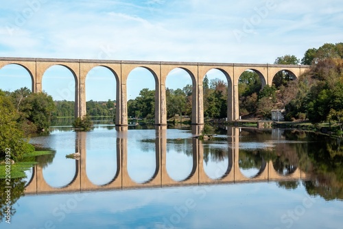 old railway viaduct over the river Vienne at L'Isle Jourdain in France built in 1884 reflecting in the water