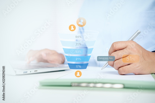 Businessman writing on document with digital marketing funnel and conversion rate optimization chart on white desk, concept of sales funnel, lead generation, and e-commerce strategy.
