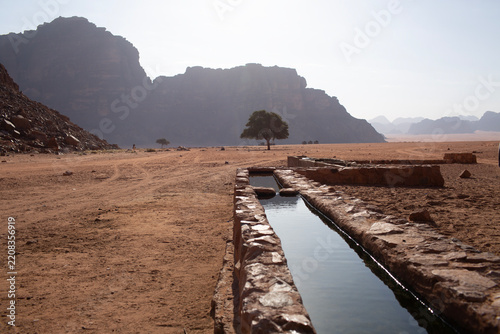 Precious water source and ancient irrigation channel in the arid desert of Wadi Rum, Jordan. Water scarcity and sustainability concept.