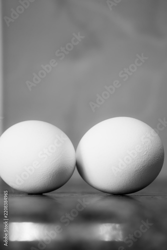 Two white chicken eggs on a wooden table, black and white close-up photo
