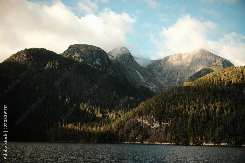 Obraz premium Forested mountains and a dark lake with shoreline buildings