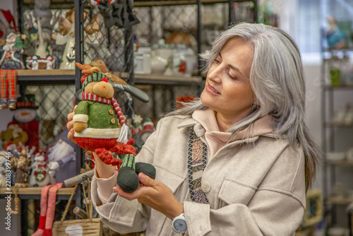Woman shopping for christmas decorations holding reindeer toy
