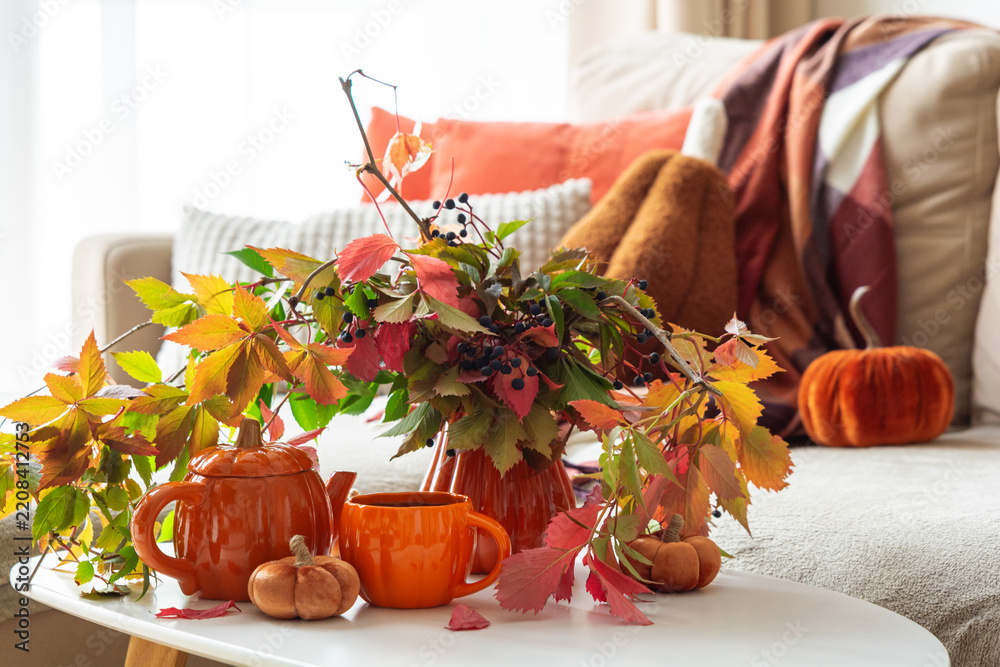 Fototapeta premium Autumn cozy scene with colorful leaves pumpkin teapot and mug on table