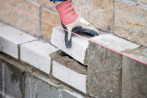 Worker lays bricks on a construction site while following guidelines on a wall