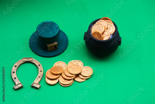 leprechaun hat with horseshoe and coins on green background