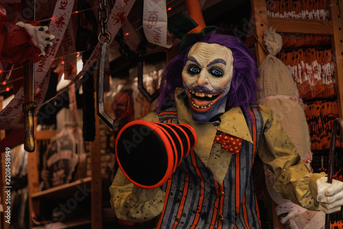Obraz na plátně Scary Halloween clown prop with purple hair and menacing grin holds striped mega