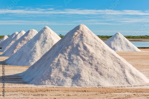 Salt piles drying in traditional coastal saltworks under blue sky