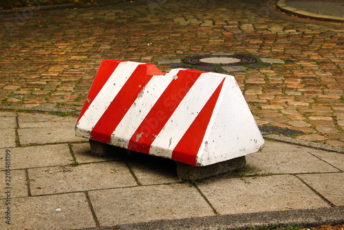 Red and white striped road barrier on paved street during construction