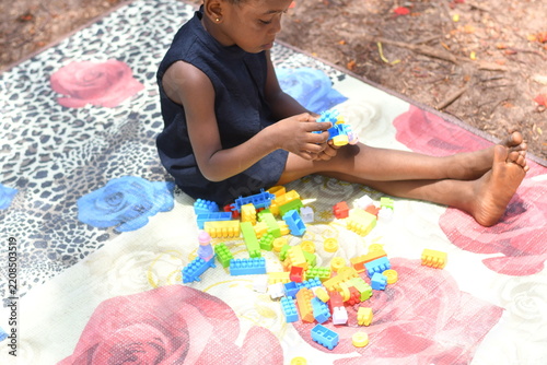 Little girl building colorful blocks tower outdoor play