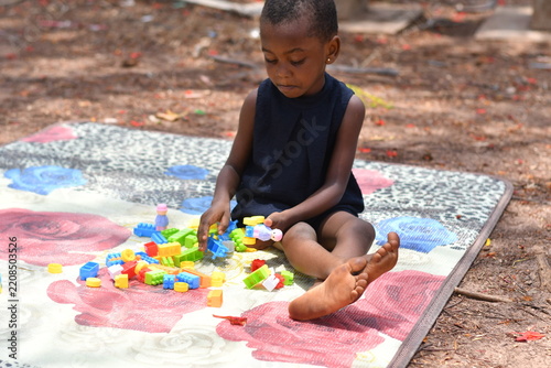 Little girl building colorful blocks tower outdoor play