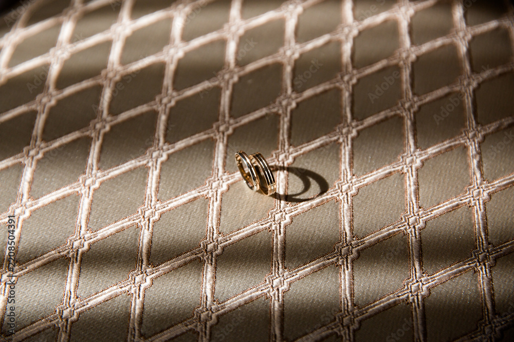 Obraz premium Gold wedding rings on quilted beige fabric