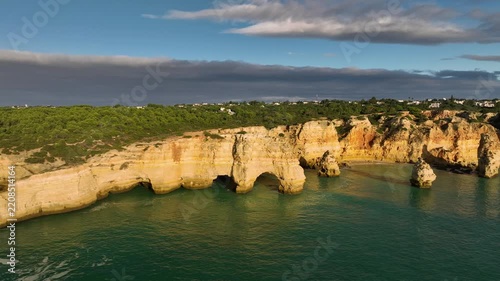 Aerial view of Praia da Marinha beach in Algarve, Portugal, with ocean cliffs, sea stacks and natural rock arches. Slide trucking shot.