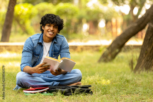 Indian male college student boy studying at park