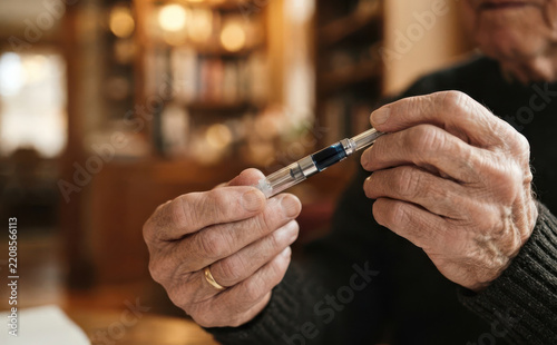Elderly man holding insulin pen in hands close up representing diabetes management and healthcare