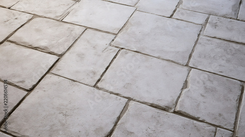 Close-up view of light gray stone paving slabs with uneven edges and visible grout lines, creating a simple outdoor texture background.