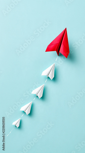 Five paper airplanes flying upwards on a blue background, with one large red plane leading four smaller white planes.