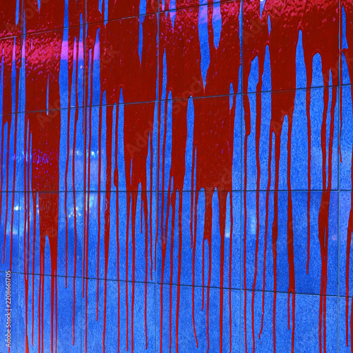 Red paint dripping down a textured blue surface background with dripping