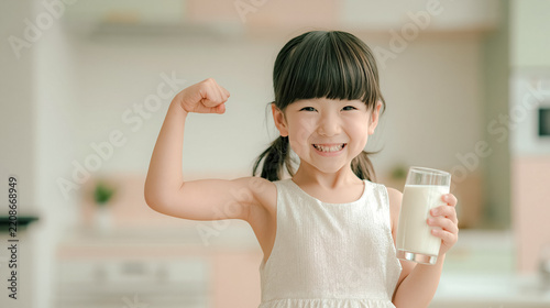 A smiling young girl holding a glass of fresh milk. Daily dairy protein consumption supports healthy bone development and childhood strength.