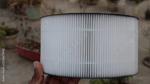 Hand holding indoor air purifier filter cartridge showing pleated details close up view
