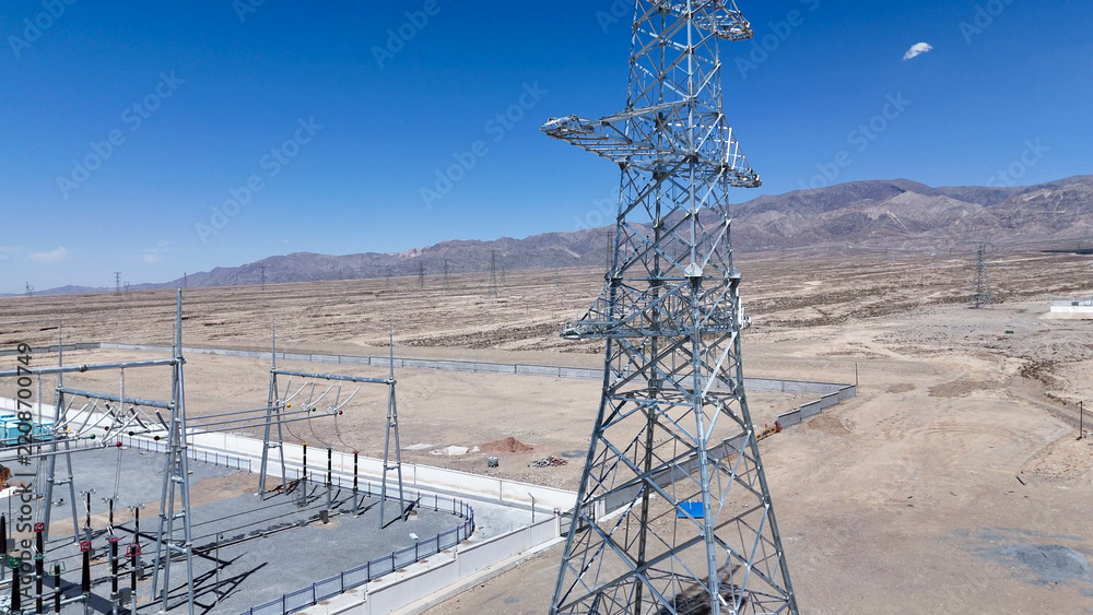 Obraz premium high voltage transmission tower and substation in desert landscape